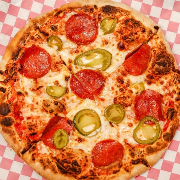 Up North Pizzeria's pepperoni and jalapeño pizza, sliced and ready to eat on a checkered paper.